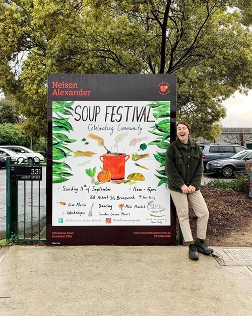 A woman standing next to a billboard she designed